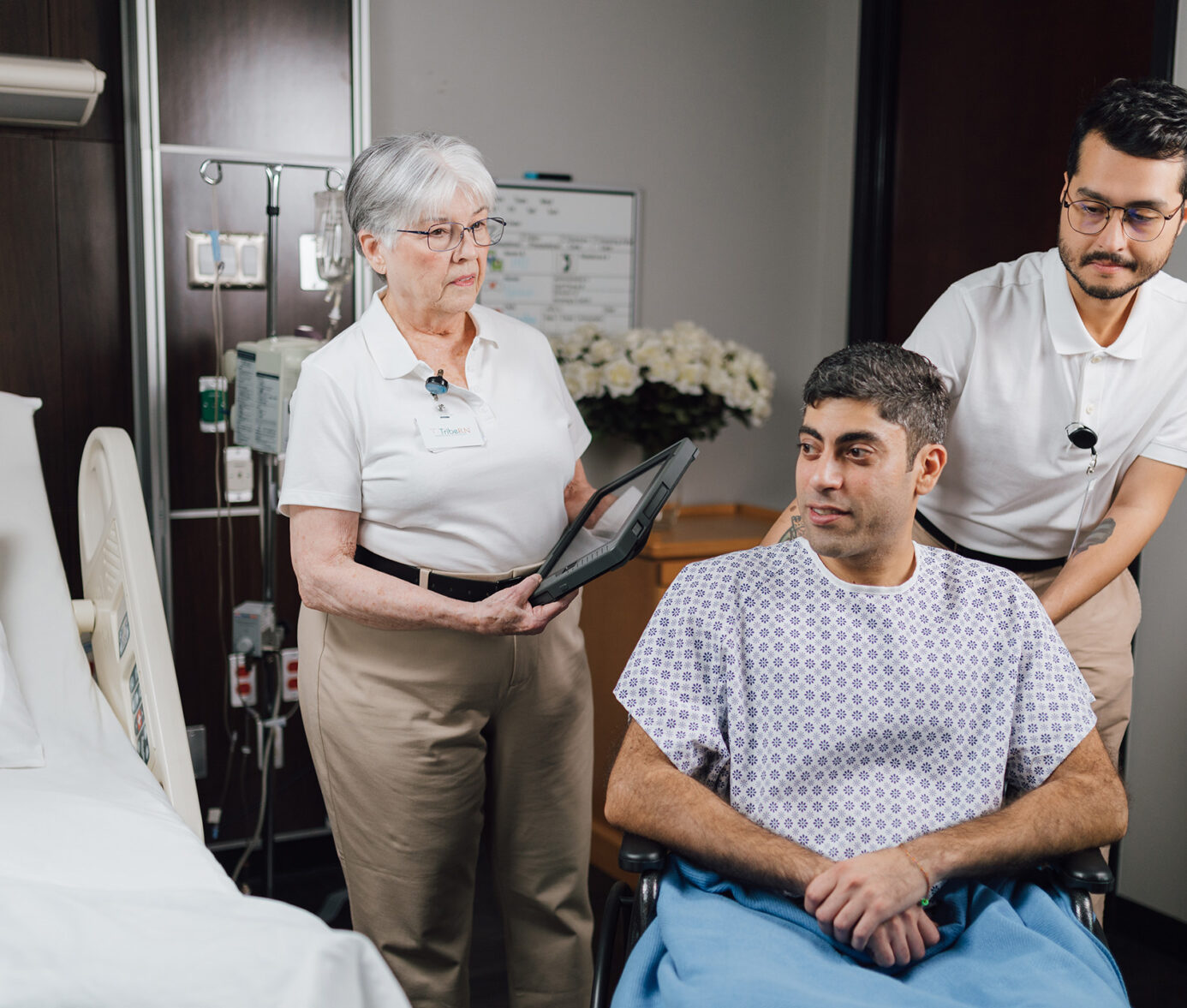 Elderly patient and healthcare workers reviewing medical records in a hospital room