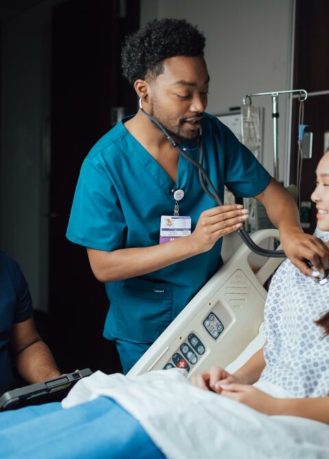 Caring male nurse monitoring patient's vitals in a hospital room, providing attentive healthcare support.