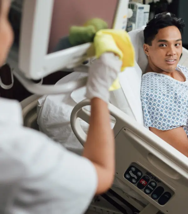 Young male patient smiles at nurse while sitting in hospital bed during interaction