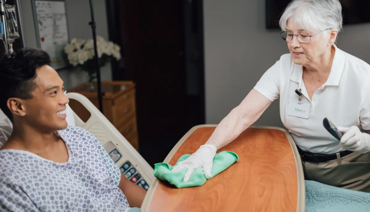 Friendly caregiver cleaning patient's hand in healthcare setting, providing attentive bedside care.