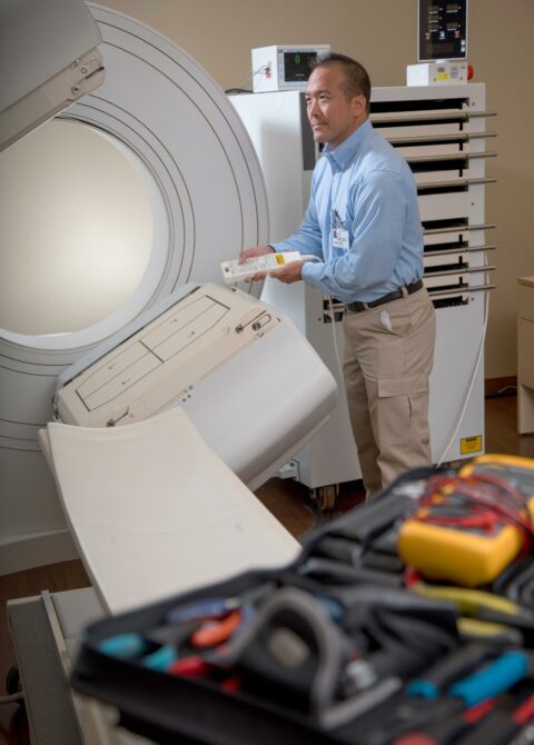 Alt text: Crothall Healthcare technician performs maintenance on medical imaging equipment