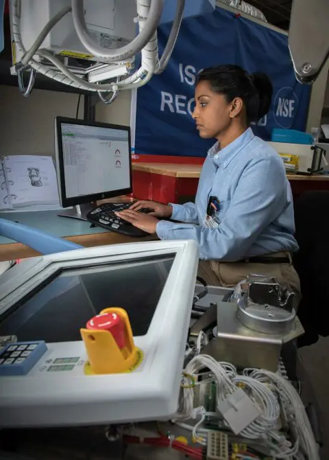 Young technician using computer for healthcare equipment maintenance in hospital radiology department