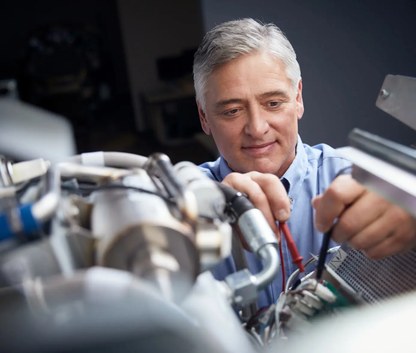 Alt text: Smiling senior male technician repairing medical equipment in a healthcare facility