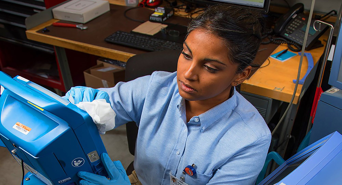 Crothall Blog Headers (5) Alt text: Technician in blue shirt and gloves working with medical equipment in a laboratory setting.