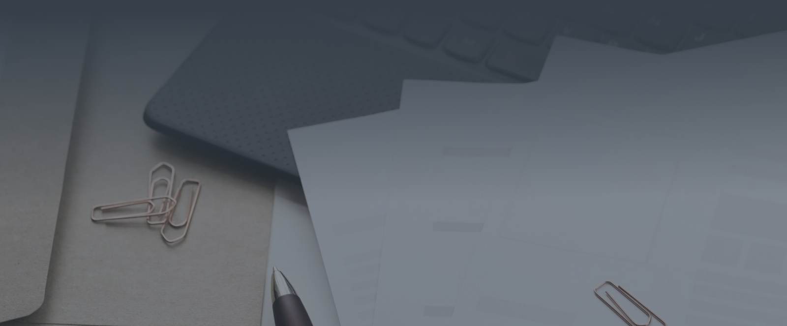 Close-up of white papers and silver paperclips against a dark gray background
