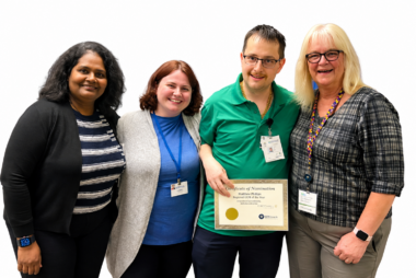 Matthew Phillips stands with colleagues while holding his Crothall Healthcare Regional GEM of the Year award certificate.